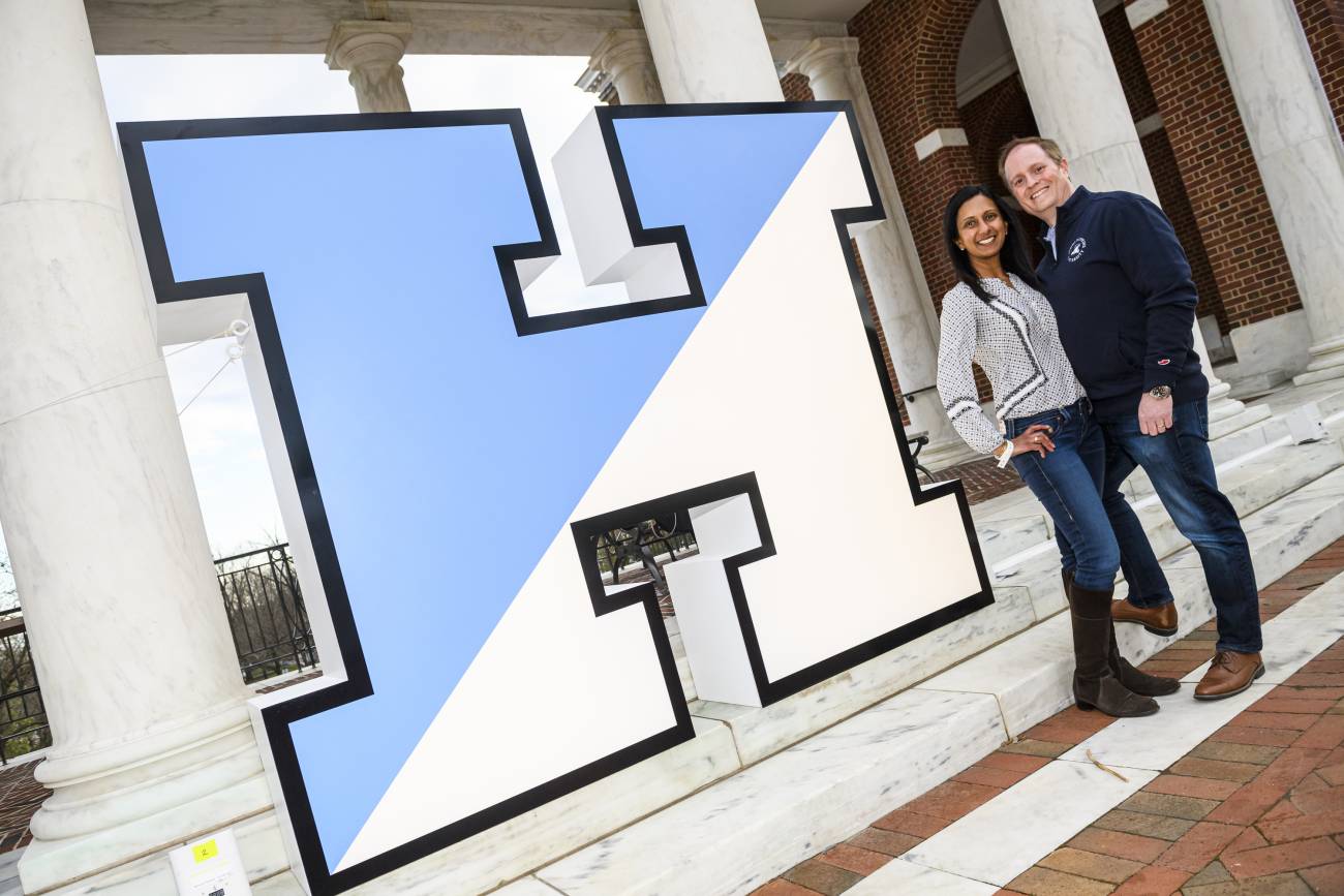 Two alumni standing next to the Hopkins H celebrating Alumni Weekend on the Homewood Campus in Baltimore, Maryland.