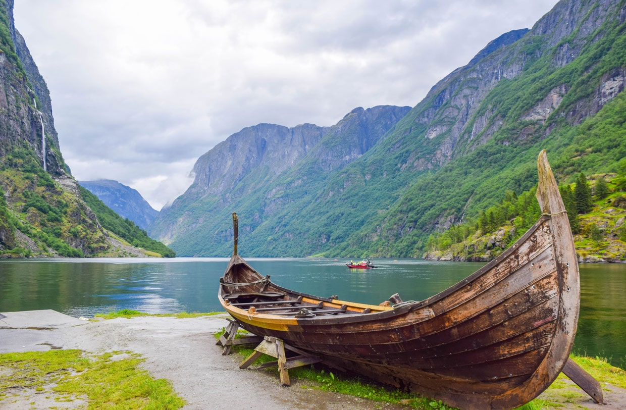 Wooden boat in front of lake and mountains in background
