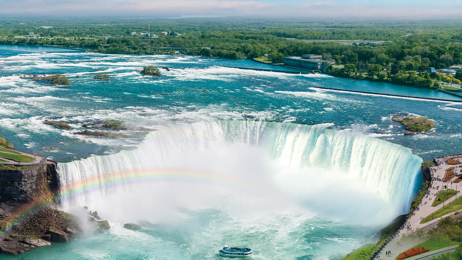 boat at bottom of Niagara falls with rainbow