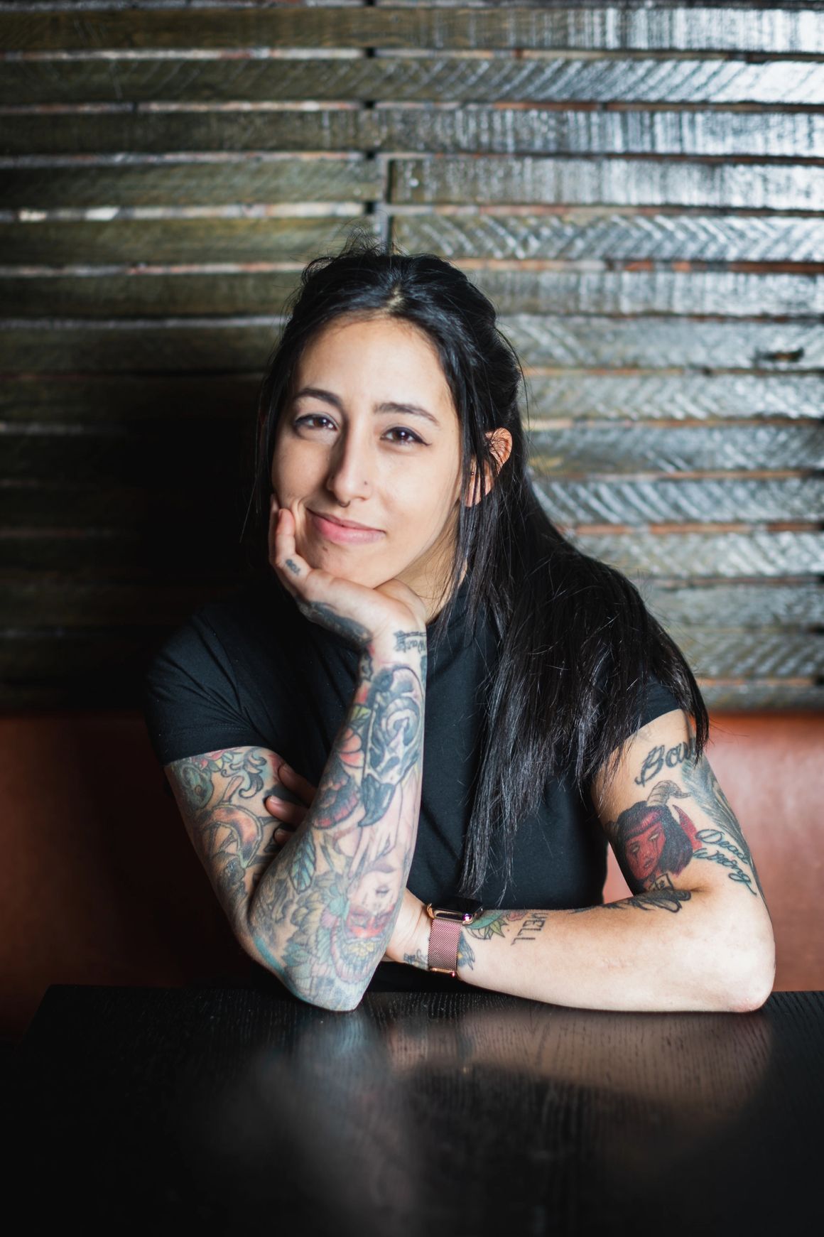 Image of Chef Halee Raff, seated at a table, with her elbow propped on table, resting her head on her hand. 